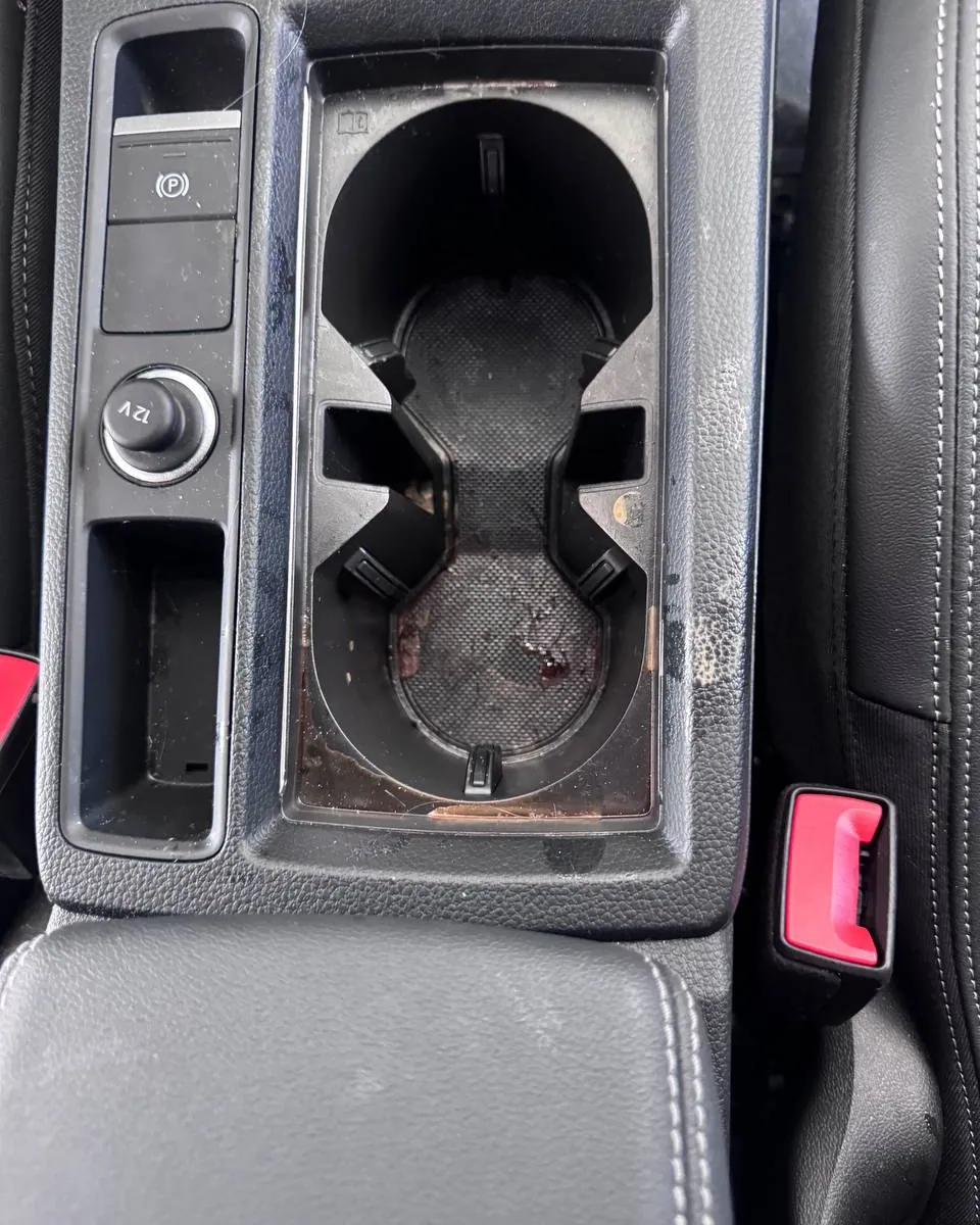 Car centre console before an interior detail in Miami — stained cup holders and ingrained grime around the gear selector